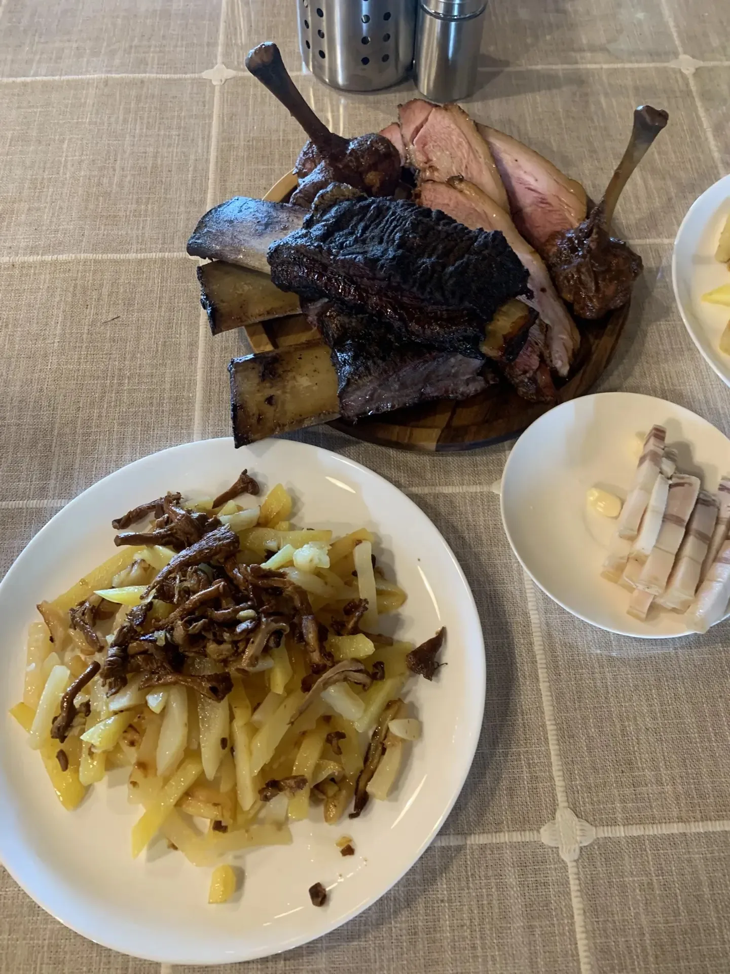 Мясное плато на деревянной доске: рёбра, голяшки и томлёное мясо с жареной картошкой и лесными грибами
